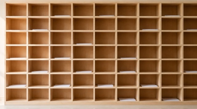 Kurs-Titelbild KI in der Verwaltung: Wand aus vielen gleich großen, unbeschrifteten Postfächern aus hellem Holz (KI-generiert)